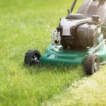 Mowing or cutting the long grass with a green lawn mower