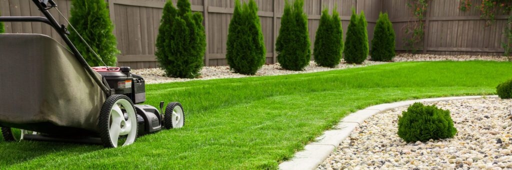 Lawn mower cutting green grass in backyard, mowing lawn for residential landscaping