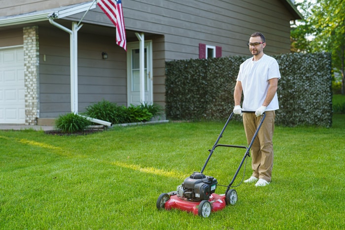 Man portrait mowing the lawn with lawnmower on the house yard